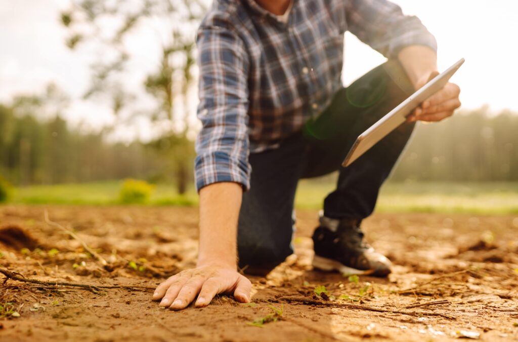 Ground Improvement Techniques - A Contractor Touching the Red Clay on a Construction Site with His Clipboard in the Other Hand