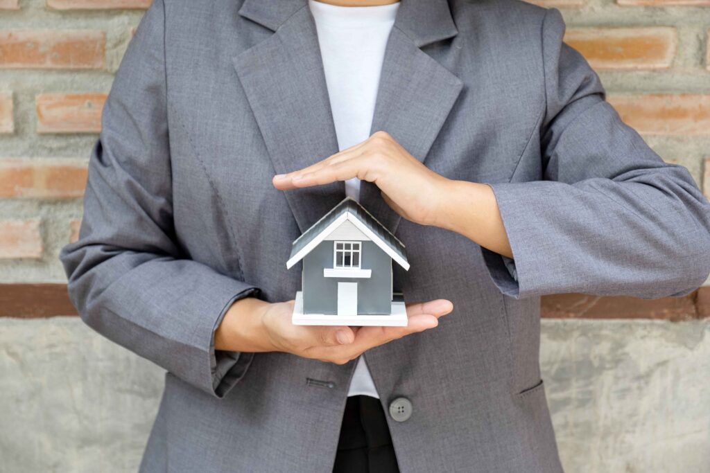 Push Pile Installation Contractors in New York - A Woman in a Suit Holding Her Hands Over a small house Model Like a Roof to Symbolize Protection