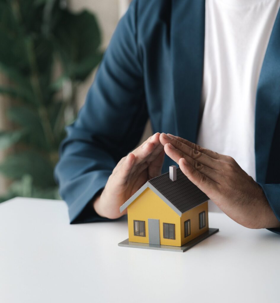 Micropile Installation Contractors in New York - A Man at a Table with His Hands Cupped Over a Small House Model Like a Roof