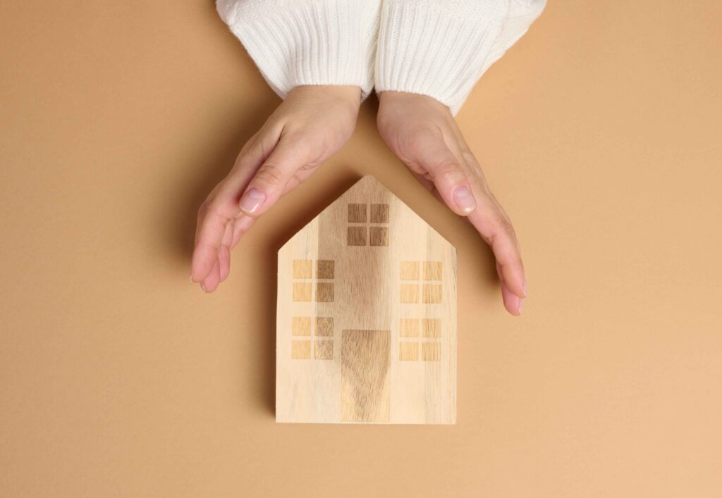 Helical Pile Installation Contractors in New York - A Woman Cupping Her Hands Around a Wooden House Model on a Table