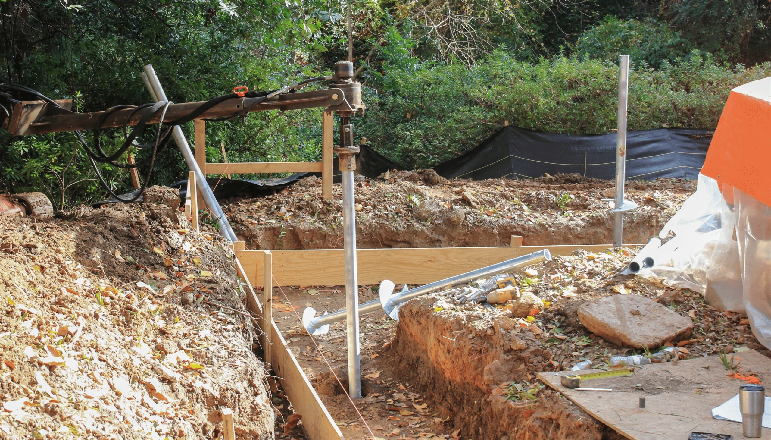 Helical Piers Installation - A Helical Pier Being Installed with Hydraulic Machinery at a New Construction Site in Clay Soil