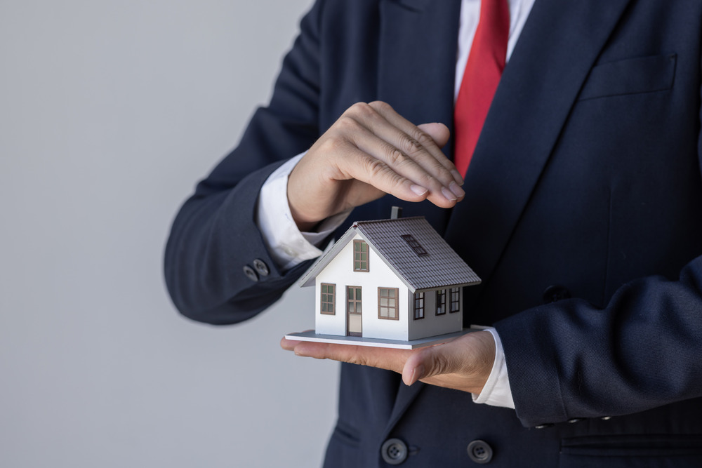 Commercial Radon Testing - A Man Cupping His Hands Over a Small House Model to Indicate Protection