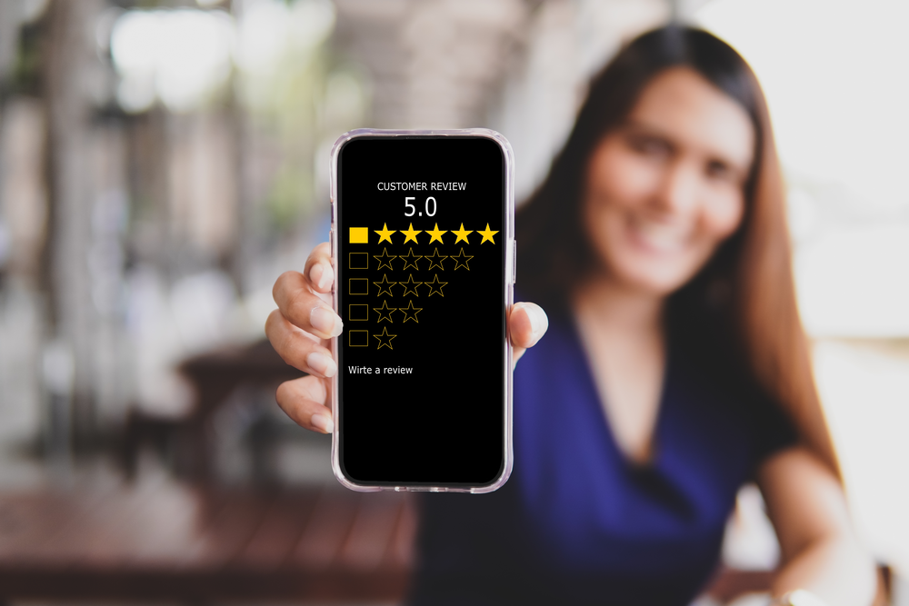 Residential Helical Piles - A Woman Holding Up a Phone Showing Off a Five Star Review