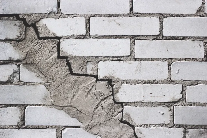 Settlement Cracks in Foundations - A Picture of Stair-Step Cracks in a White Brick Foundation