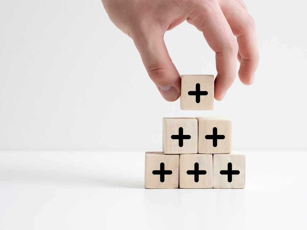 Chemical Grouting - A Man Stacking Little Blocks with Plus Signs on them in the Shape of a Triangle