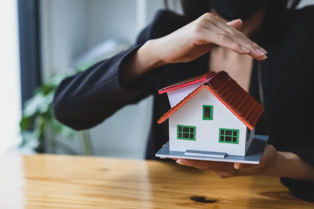 Compaction Testing - A Woman Cupping Her Hands Over a House Model to Symbolize Security