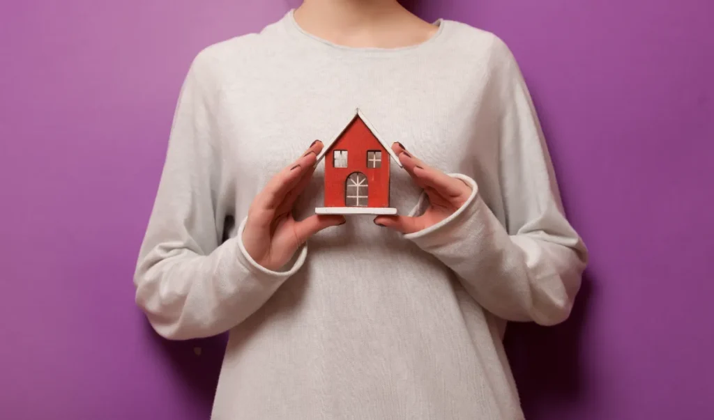 Push Pier Installation - A Woman Holding a Small House Model in Her Hands As If to Protect It