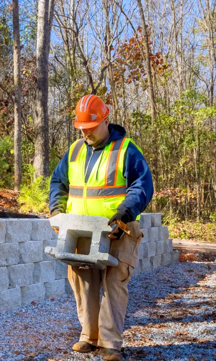 Natural Stone Retaining Wall Construction - A Man Carrying Retaining Wall Pieces Near a Retaining Wall