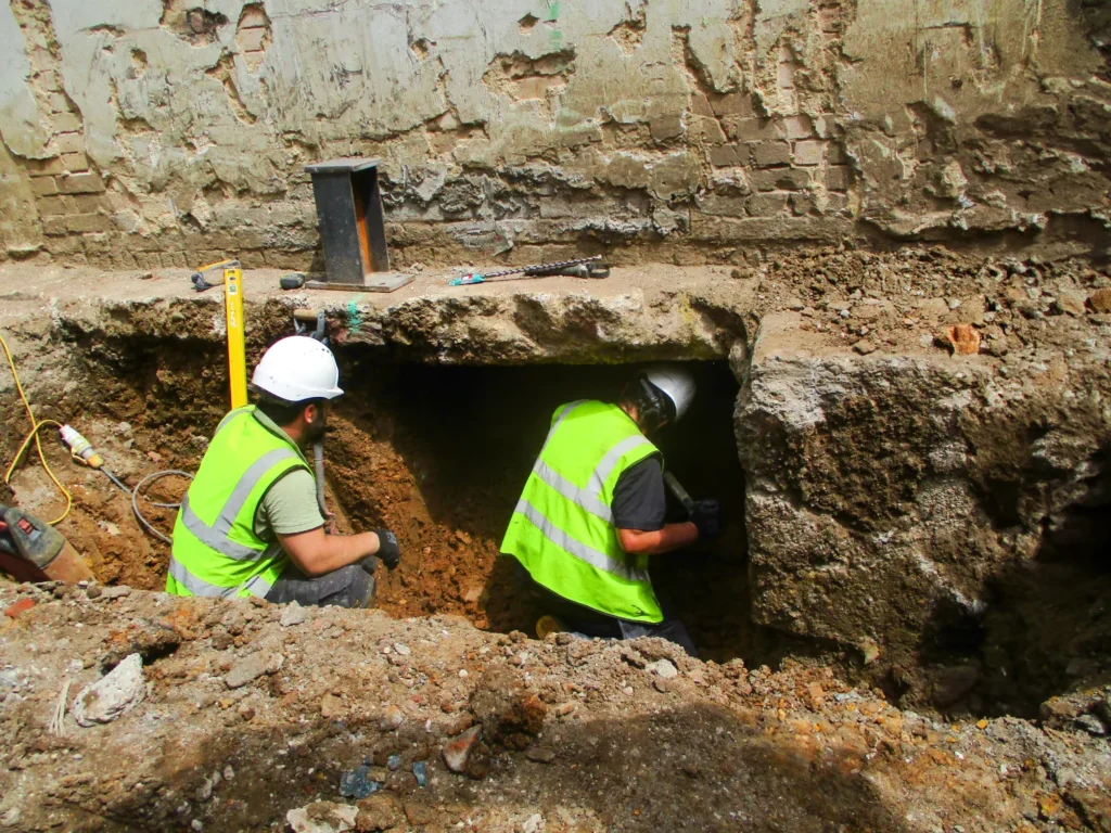 Foundation Erosion Repair and Prevention - Two Construction Workers Working on a Building Suffering from Foundation Erosion