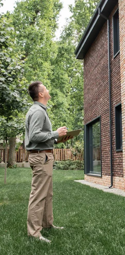 Basement Wall Reinforcement - A Foundation Inspector Looking for Damages to a Building's Exterior