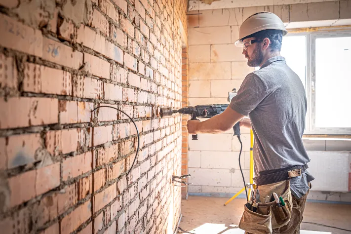 Basement Wall Reinforcement - A Man Drilling a Hole in a Basement Wall