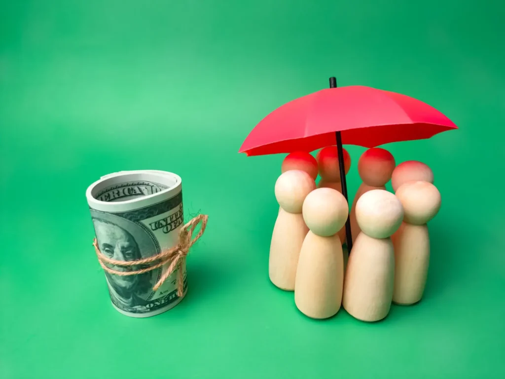 House Lifting Contractors in Long Island, NY - A Group of People Figures with an Umbrella Above them and a Roll of Money Next to Them Indicating the Benefits of Safety and Insurance Rates Savings for House Lifting for Flood Prevention