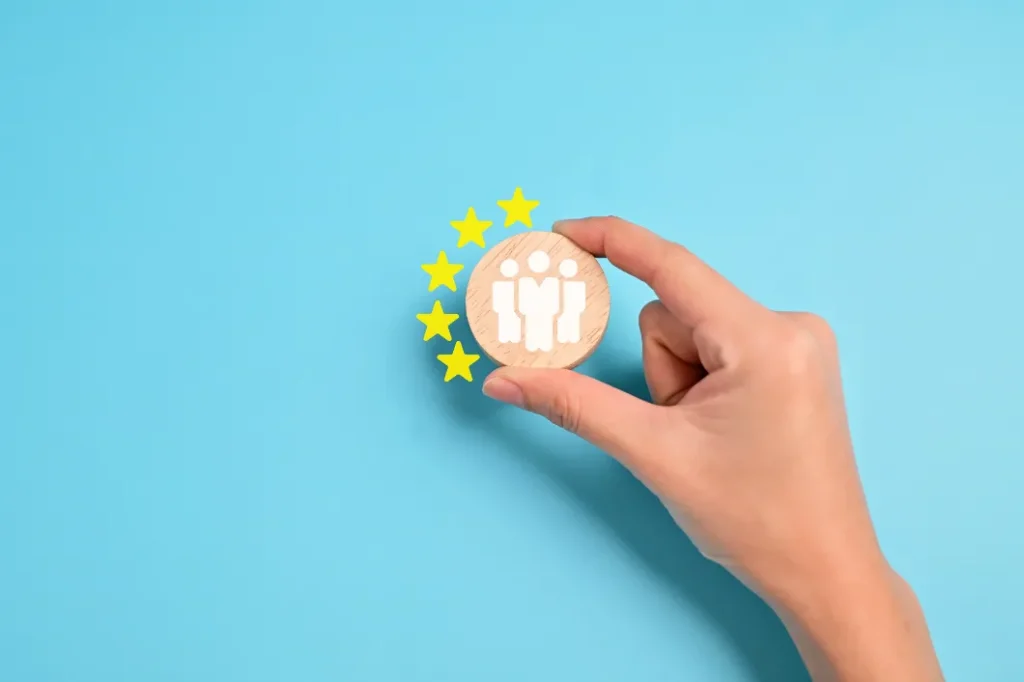 Temporary Flood Barriers - Woman Holding Up a Wooden Circle with People Figures on it with Five Stars Around it